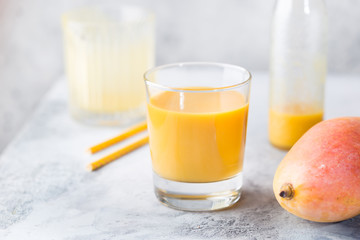 Tropical Mango smoothie in a glass and fresh mango on a light background. Mango shake. Tropical fruit concept.