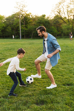 Two cheerful brothers playing football on the lawn