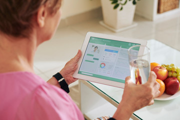 Senior woman monitoring her health with help of application on tablet computer