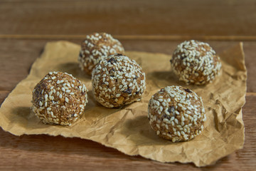 Healthy organic energy granola bites with nuts, cacao, prunes, sesam and honey - vegan and vegetarian raw snack on wooden background