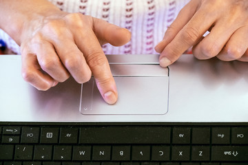 The hands of a caucasian old woman with natural manicure and  touchpad of a notebook. Close-up. Know more about modern technologies. Black keyboard. Top view