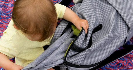 Baby look in bag that the search and gets out clothes and things of the bag