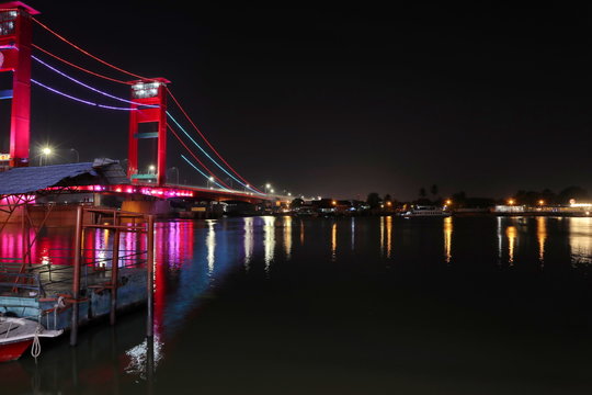 Palembang's Ampera bridge is photographed at night, with natural lighting and slow speed photography techniques.