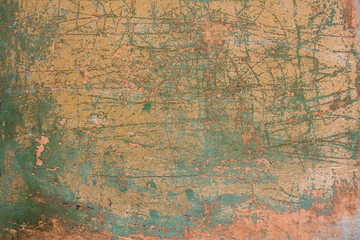 old shabby pink yellow concrete wall with cracks, deep scratches and stains of green paint and dirt. rough surface texture
