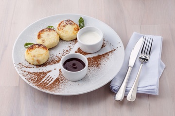 Cheese pancakes with currant jam and sour cream on a plate