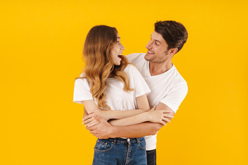 Portrait of young couple man and woman in basic t-shirts smiling and hugging together