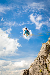 Fototapeta premium Young slackliner man balancing on a slackline betweend two rocks. Highline with a beautiful natural landscape behind