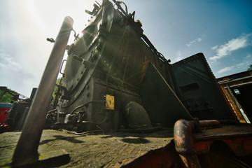 Wide-angle shot against the sun from a historic black locomotive made of iron