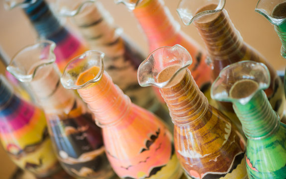 bottles with multicolor sand pictures inside on egyptian market shelfs closeup