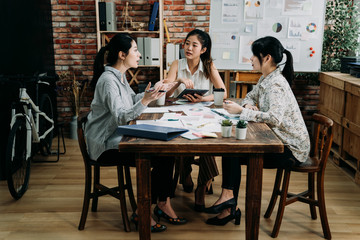 Confident and successful team work. full length of young modern female people in smart casual wear discussing business while sitting in creative office. girls employees concentrated listen to leader.
