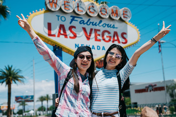 Attractive gorgeous travel girl partners with beaming grins and posing with victory finger sign...