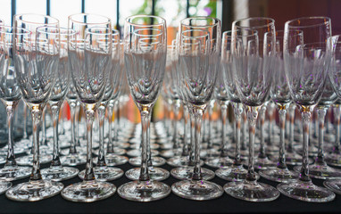 Several rows clear transparent, clean glasses for wine and champagne on counter prepared for drinks.