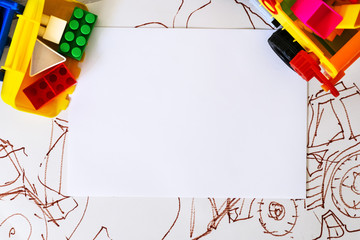  White paper surrounded by a toy multi-colored dump truck and a tractor with plastic cubes in the background illustration with a tractor. Concept banner. Mockup. Top view. Flat lay. Copy space