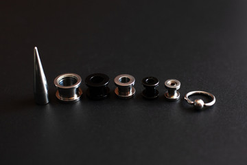 set of accessories for piercing on a dark background