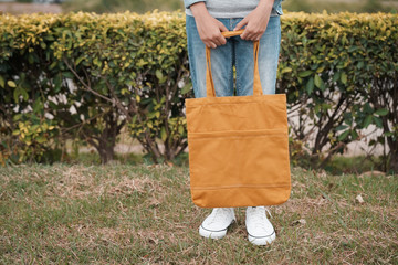 hipster woman with yellow tote bag on green grass background