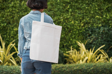 young girl holding white fabric bag at park