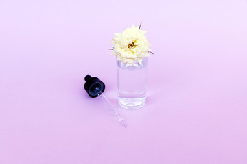 Glass bottle with pipette with oil or serum, with white rose flower on delicate background. Concept: organic bio cosmetics, vegetable oils, serum collagen, skin care