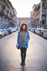 young woman standing in the middle of the street