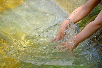 Young kids hands splashing around water in fountain to cool off, as the heat waves continue.  Close up on the water splash and the hands