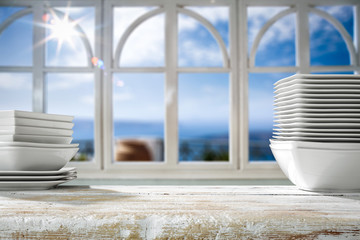 White wooden desk in kitchen and blurred background of window and summer landscape of sun and sea 