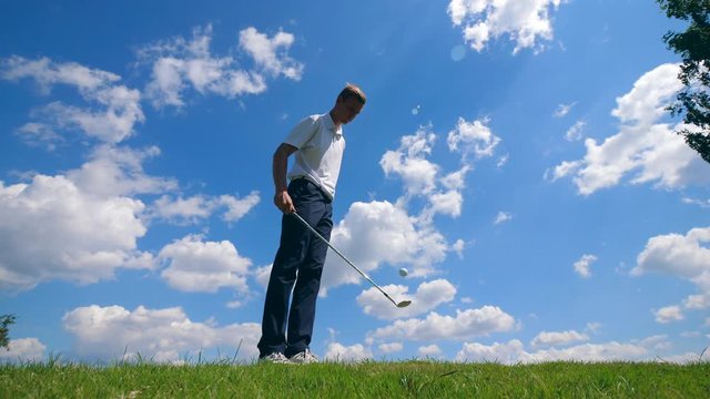 A man is playing tricks with a golf club and a ball