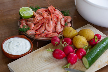 Сucumber, radish, cooked potato, white sauce and shrimps with lime as ingredients for salad