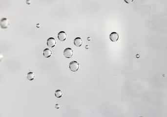 Gas bubbles of refreshing sparkling water attached to the glass on bright background with copy space.