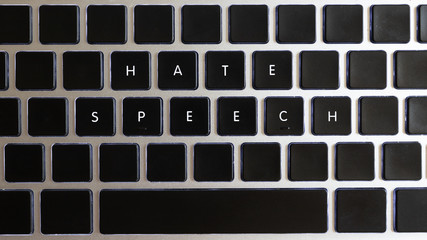 Concept of problems of today internet. Hate speech caption isolated on notebook keyboard with blank keys.