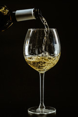 White wine being poured in a wine glass on a dark background