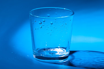 A glass with water drops  on a dark blue background close up