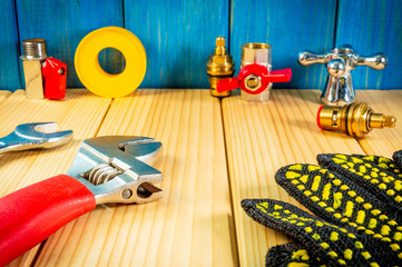 Hand tools for plumbing and parts on wooden background with space for advertising.