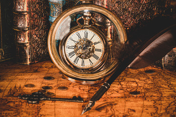 Antique clock on the background of a magnifying glass and books. Vintage style. 1565 old map of the year.