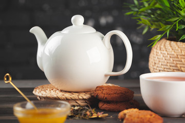 glass teapot with cup of black tea on wooden table