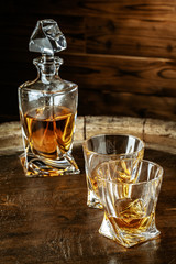 Two glasses of brandy or cognac and bottle on the wooden table