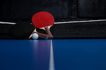 Two ping pong rackets. Table tennis rackets and a ball on a blue tennis table