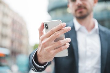 Young businessman holding smartphone in hand