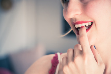 Attractive red lip stick: Blonde young woman with colorful nail polish is looking herself in the mirror. Cut out of the face.