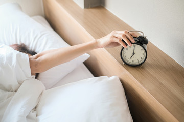 Woman sleep on the bed turns off the alarm clock wake up at the morning, Selective focus.