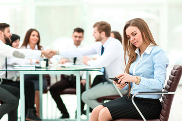 young employee with a smartphone on the background of business team