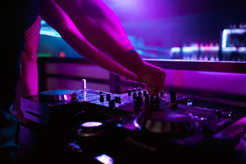 DJ turntable console mixer controlling with two hand in concert nightclub stage.