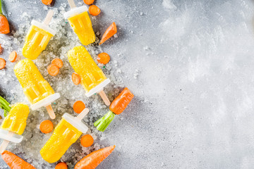 Vegetable gelato. Vegan carrot ice cream popsicles with organic baby carrots, old rustic wooden background.