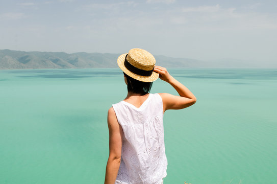 young woman tourist looking forward near Sevan lake , back view