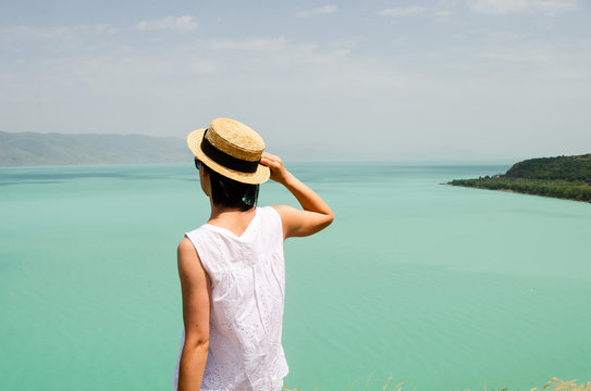 young woman tourist looking forward near Sevan lake , back view