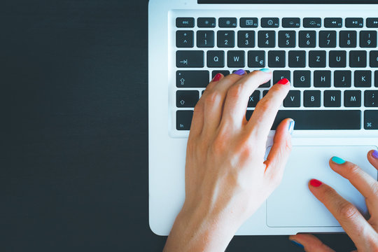 Home office or online shopping: Woman fingers with colorful nails are typing on a notebook keyboard