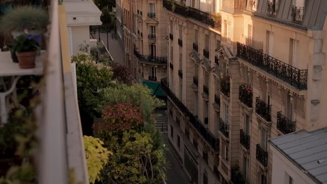 Top view on cozy balcony full of plants with the table and chairs on it and street in Paris on warm summer evening
