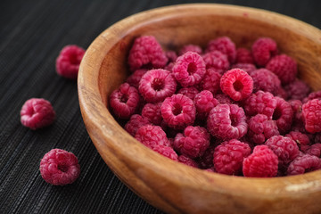Ripe raspberries in a wooden bowl