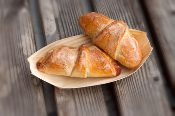 Homemade croissants in a bio dish, on the wooden background.