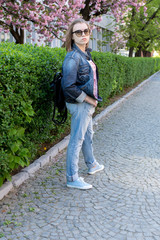 Fototapeta premium brunette teen girl in glasses walking in a flowered sakura park. walk in early spring