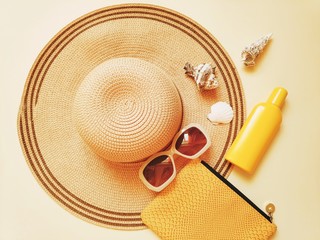 Summer holidays photo. Sun hat, yellow clutch bag, sunscreen lotion and seashells. Flat lay fashion...