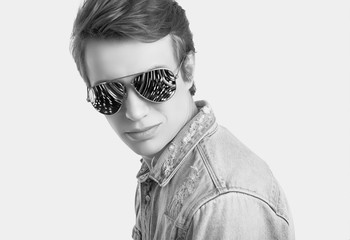 Handsome hipster man in fashion sunglasses wearing jeans jacket